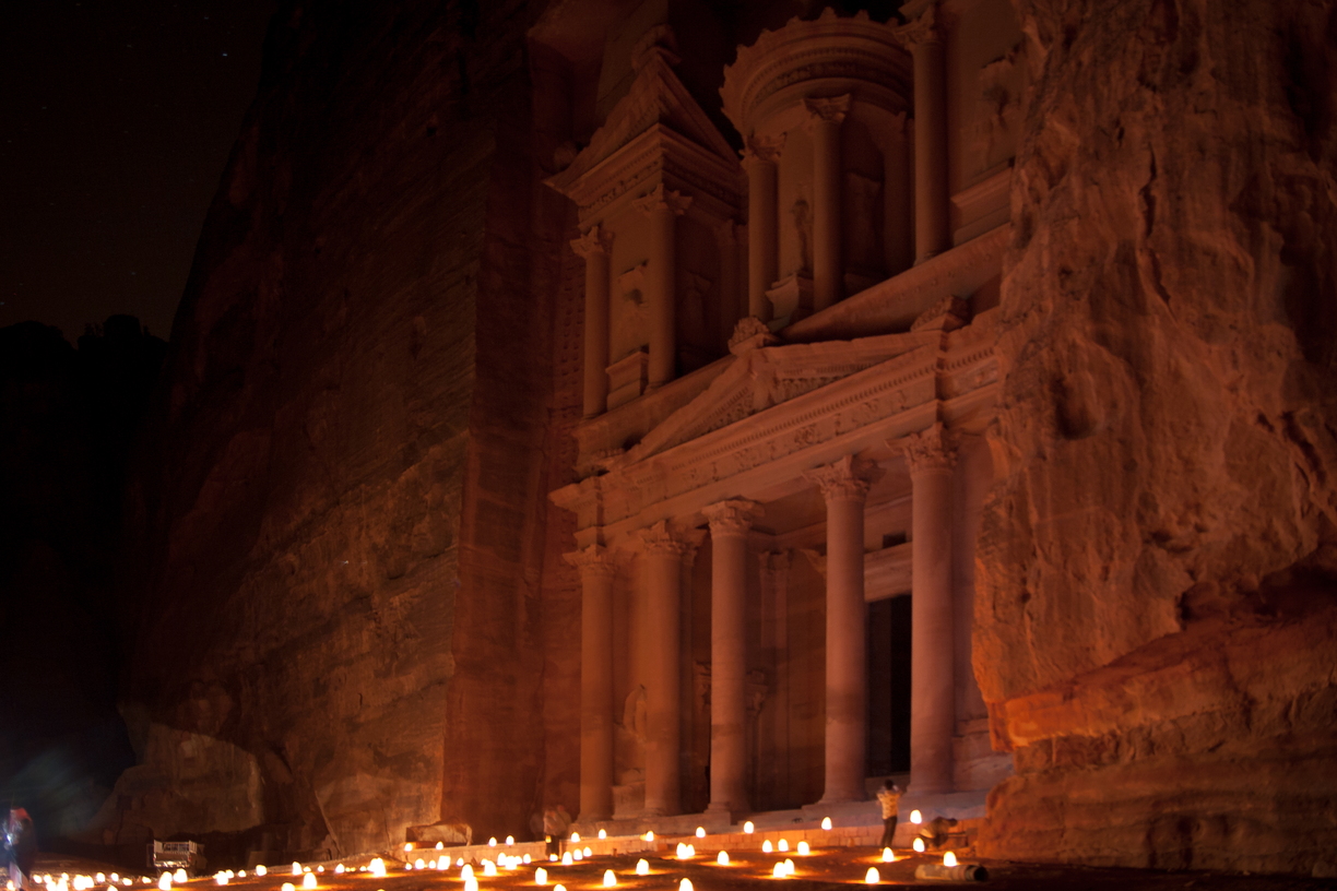 The Treasury in Petra, Jordan, is lit by candles at night as the stars appear overhead.